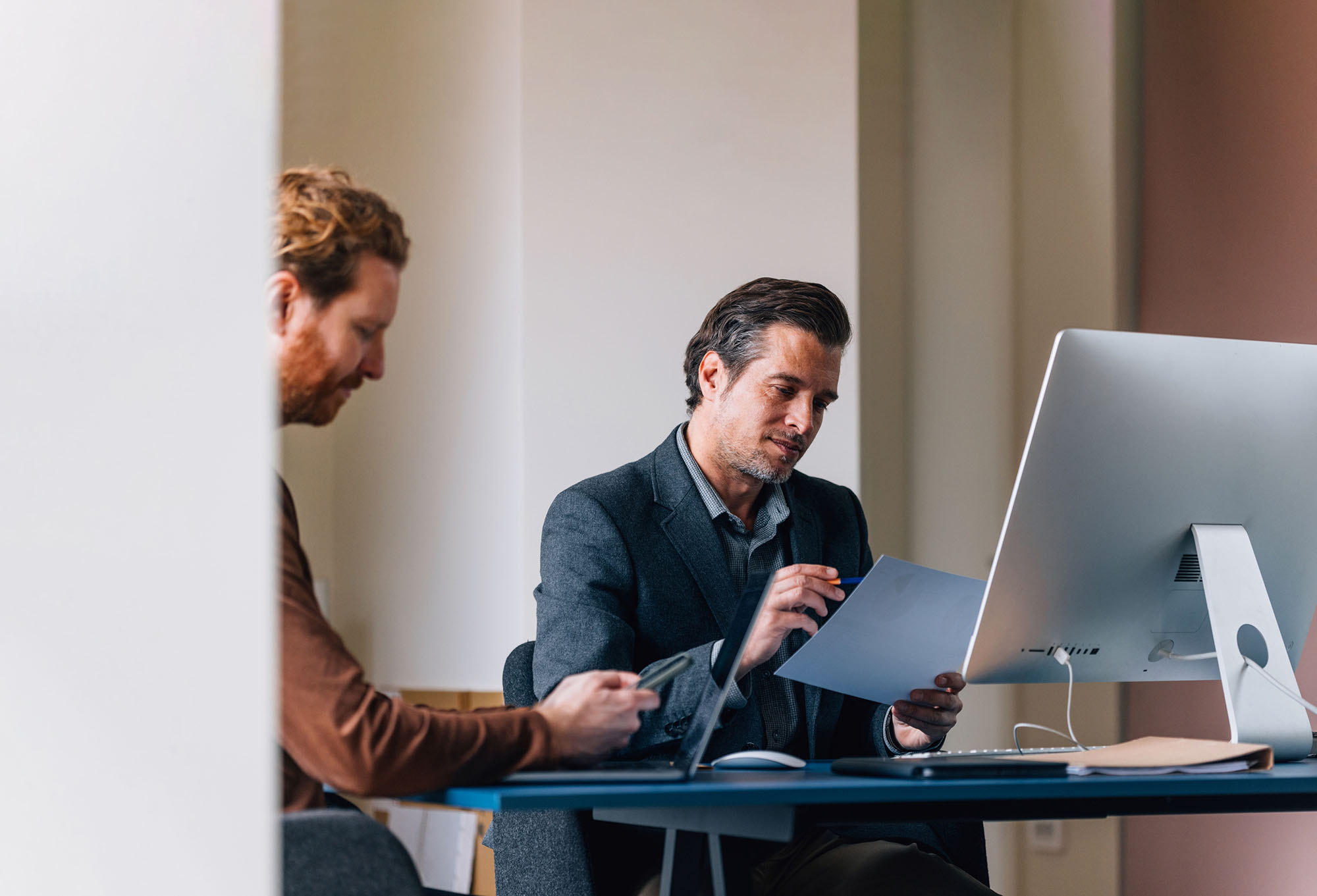 Two professionals reviewing cybersecurity and operational risk documentation in a modern office